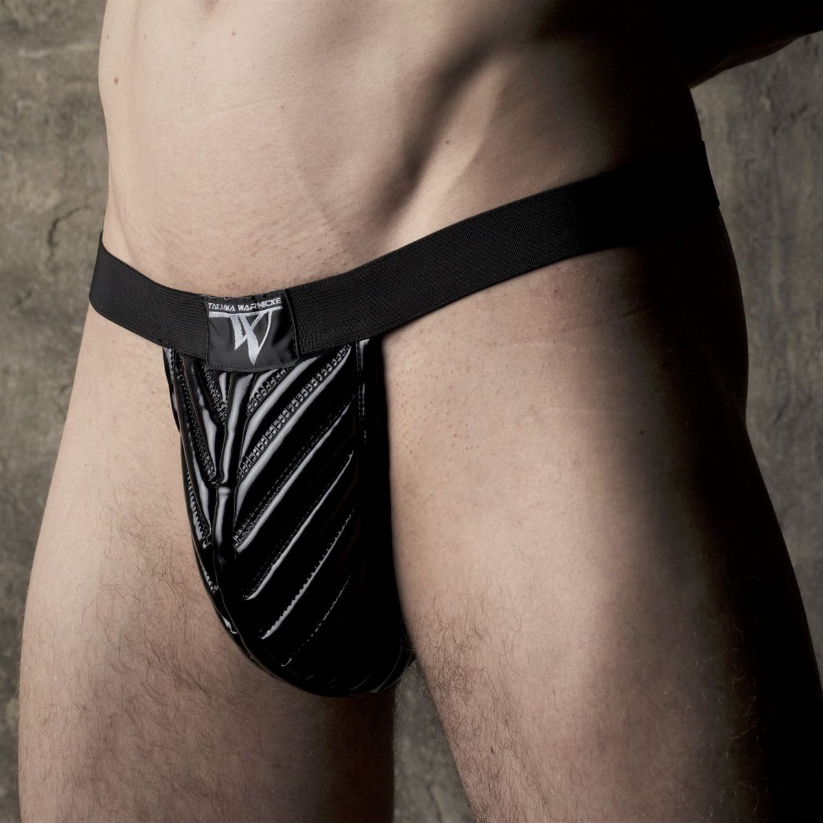 Trigo String – black glossy pouch with ribbed leather details, front view