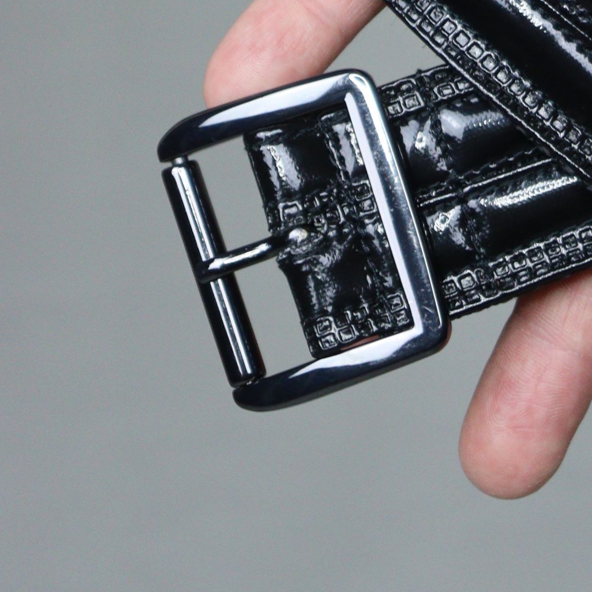 Gun Metal Belt – glossy black PVC with stud embellishments and silver-tone buckle, close-up detail