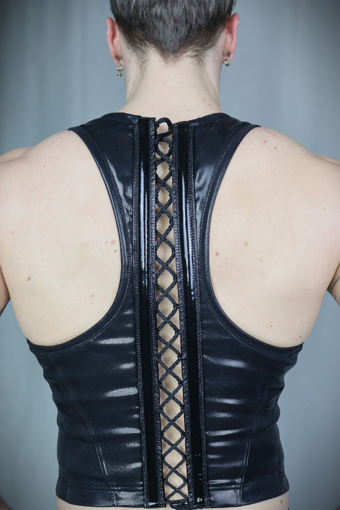Serratus Top – glossy black leatherette sleeveless top with side-panel lacing, back view