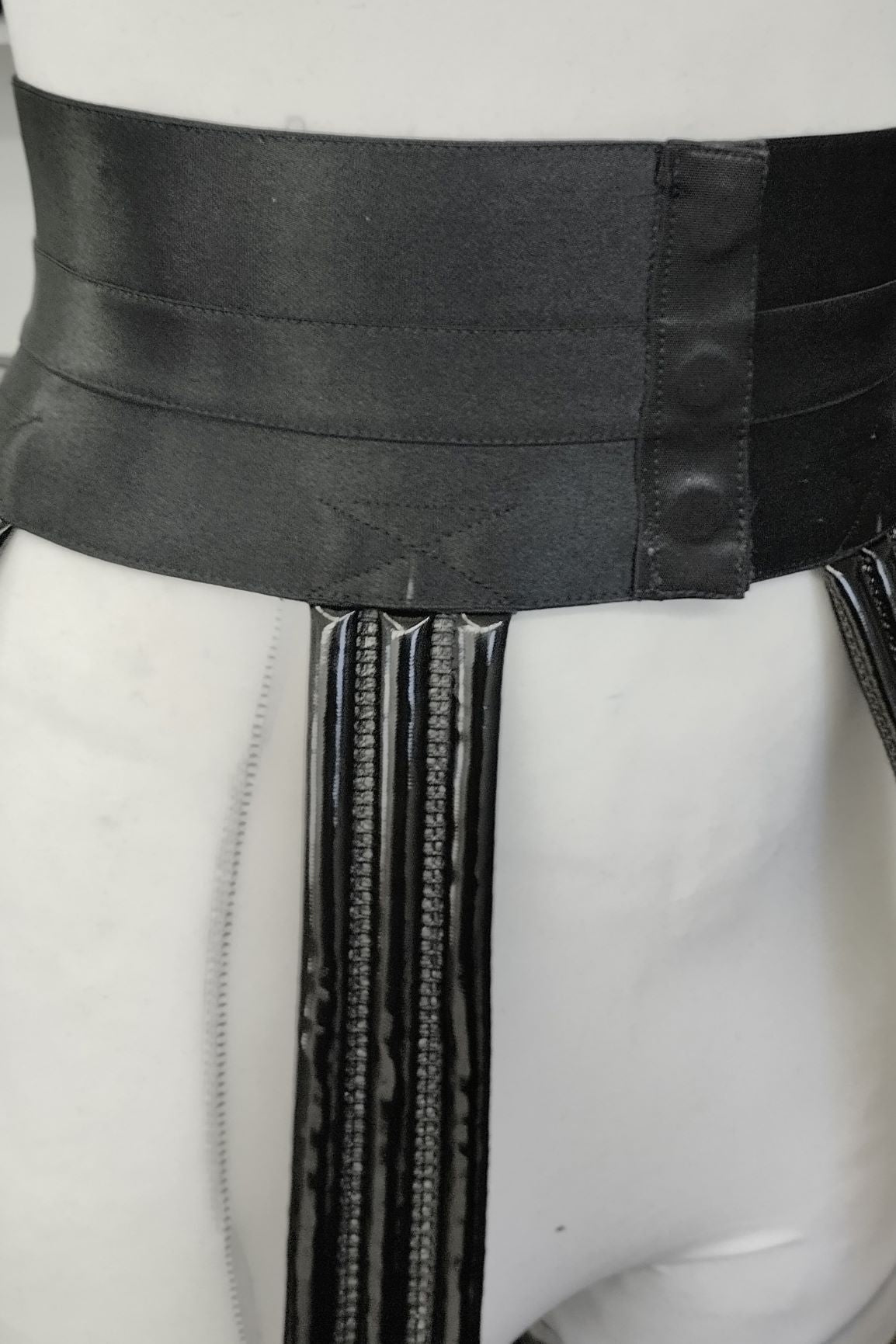 Crinoline – glossy black waistband with ribbed vertical hoop supports, close-up