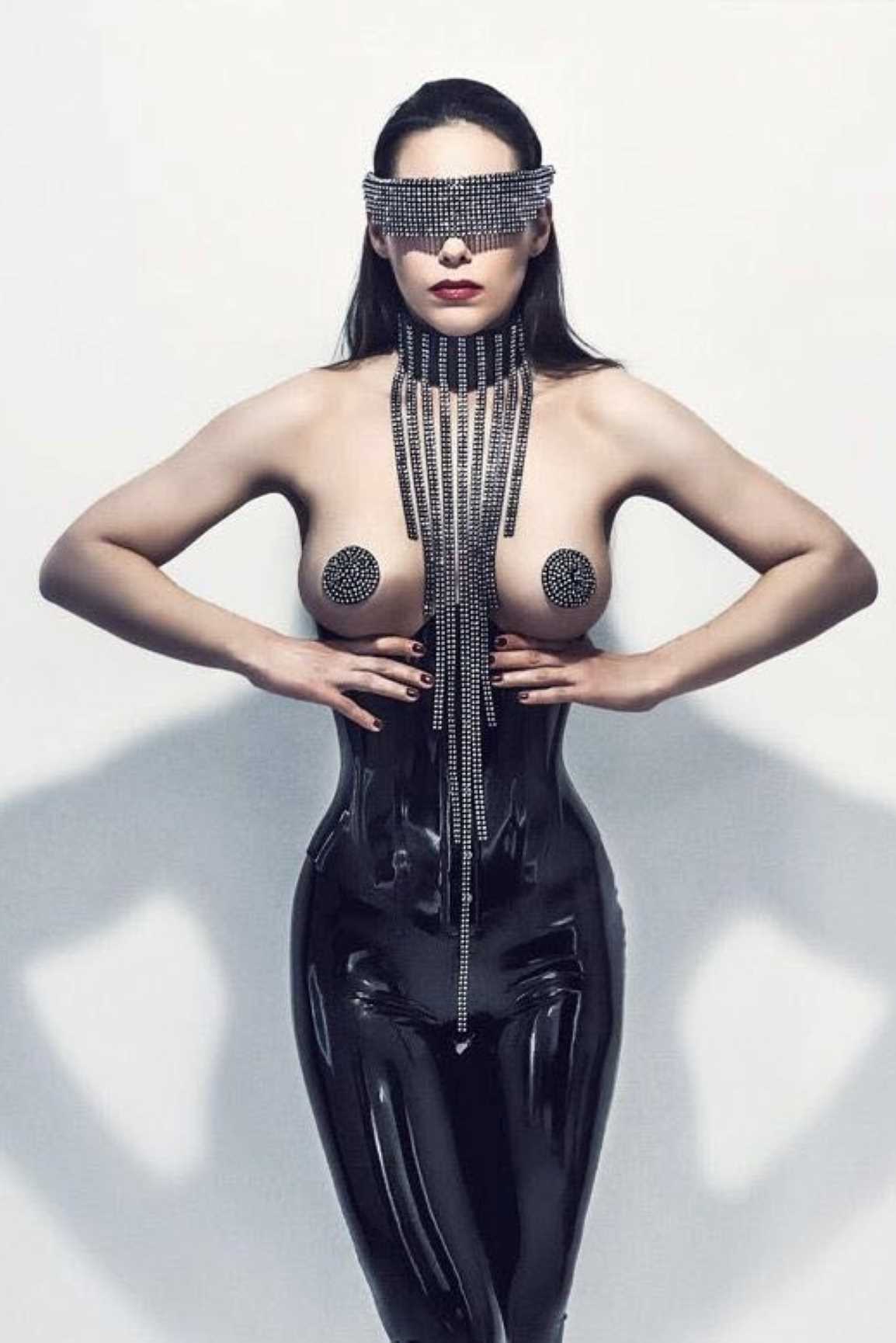 Saturna – glossy black latex bodysuit with studded harness and mask, front