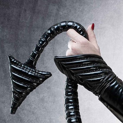 Tail DK – glossy black PVC tail with metal buckle details and ribbed segmentation, close-up