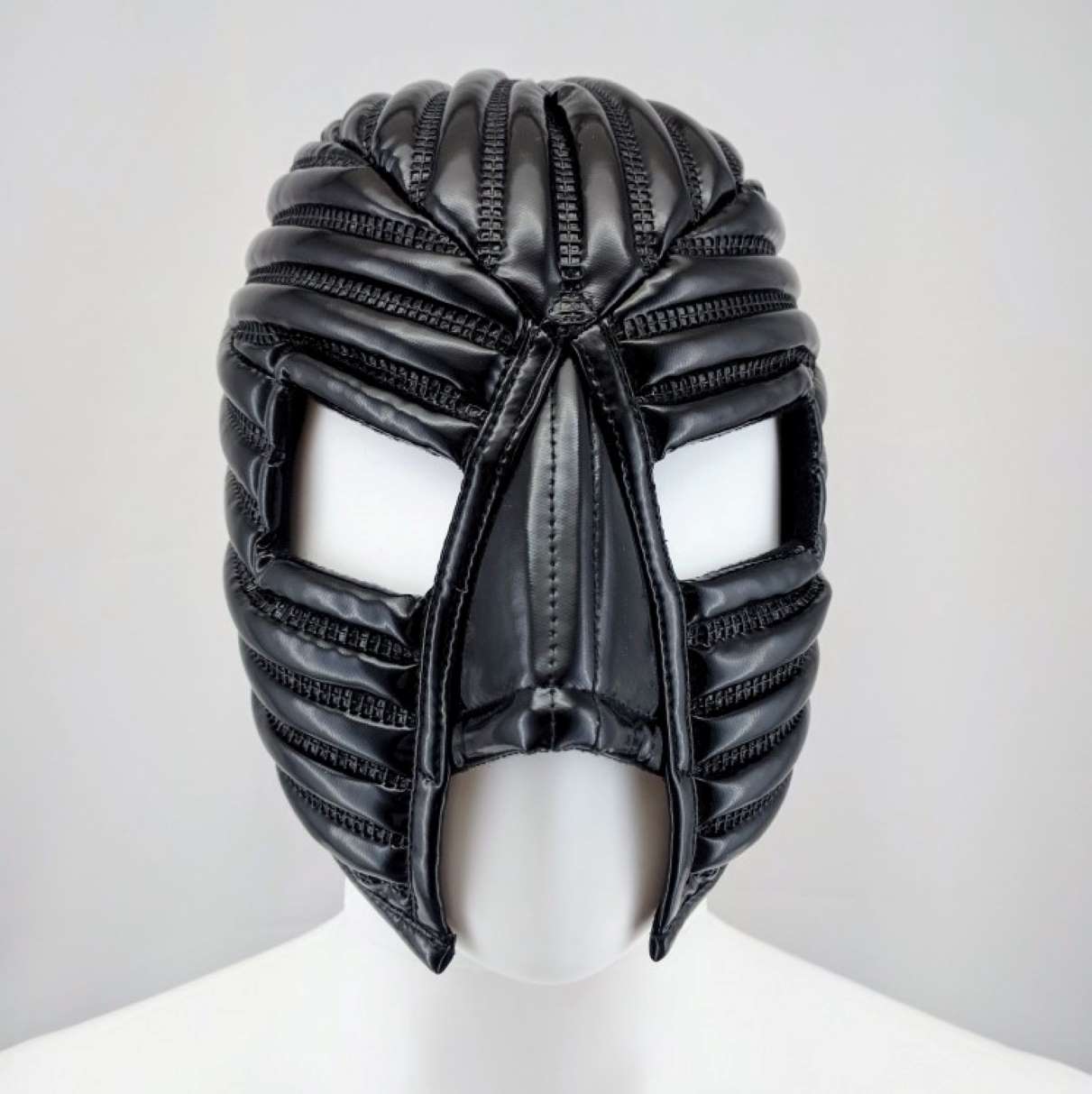 Warrior Mask – glossy black PVC with radiating horizontal ribs and eye openings, front